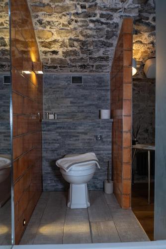a bathroom with a toilet and a brick wall at Gileston Manor-Self catering in Saint Athans