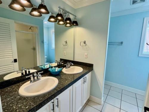a bathroom with two sinks and a large mirror at Moonlight Sonata-Beachfront-Community Pool in St. George Island