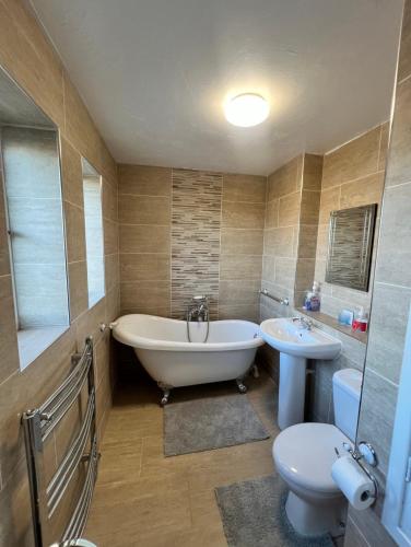 a bathroom with a tub and a toilet and a sink at Corby Guest House in Corby