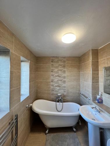 a bathroom with a tub and a sink at Corby Guest House in Corby