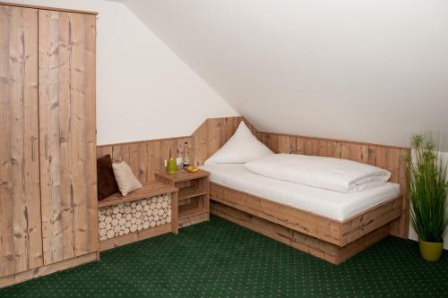 a room with a bed and a wooden wall at Hotel Hutzenthaler in Bruckberg