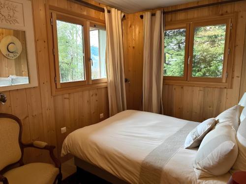 une chambre avec un lit et deux fenêtres dans l'établissement Les Chalets de Megève, confort et tranquillité, à Megève