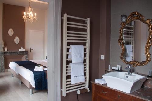 een badkamer met een bed, een wastafel en een spiegel bij Château de l'Aviette in Givet