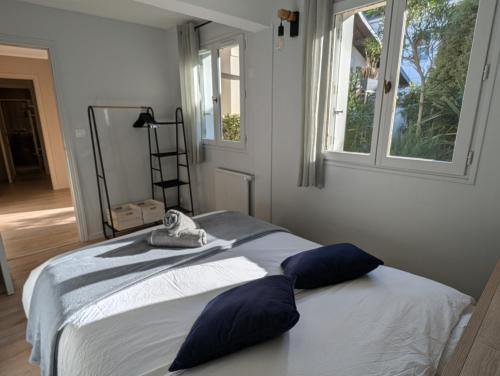 a bedroom with a bed with blue pillows and a window at Maison typique, centre-ville, jardin ville haute in Pornic