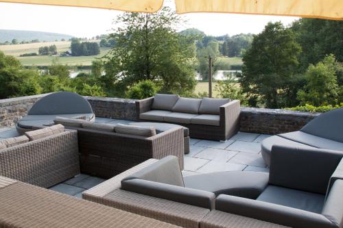 a patio with couches and chairs and a stone wall at Chateau de l Aviette - Rancennes in Givet