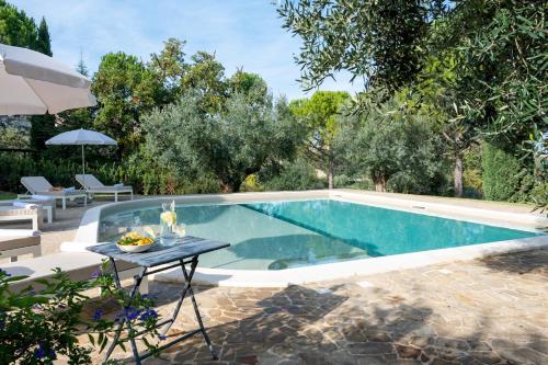 a swimming pool with a table and an umbrella at VILLA CHERUBINI 8&1, Emma Villas in Cingoli