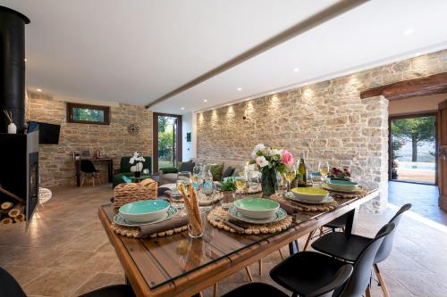 a dining room with a table and a stone wall at VILLA CHERUBINI 8&1, Emma Villas in Cingoli