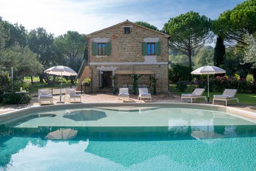 a pool with chairs and umbrellas in front of a house at VILLA CHERUBINI 8&1, Emma Villas in Cingoli