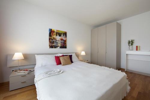 a white bedroom with a large white bed with red pillows at CITY STAY - Nordstrasse in Zürich
