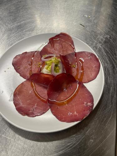 a white plate with slices of meat on a table at Il Borgo Dei Celti in Fiumalbo