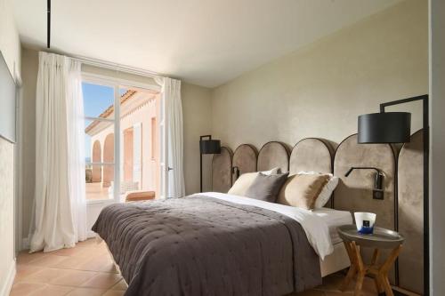une chambre avec un grand lit avec une grande fenêtre dans l'établissement Cannes superbe villa rénové, au Cannet