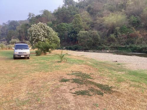 a truck parked in a field next to a river at My camper van 1 in Lamphun