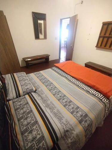 a bedroom with a bed with an orange blanket at Depto Cura Gaucho in Mina Clavero