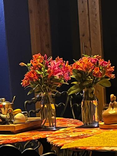 two vases filled with flowers sitting on a table at La Estancia de la Pradera Cabana Fiba in Nobsa
