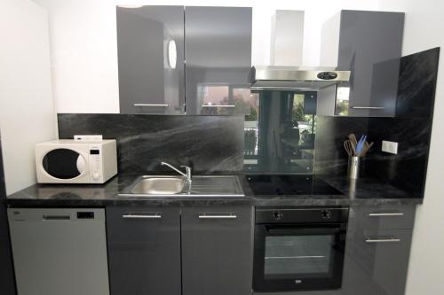 une cuisine avec un évier et un micro-ondes dans l'établissement Modern apartment with terrace and beach 5 min away, à Fréjus