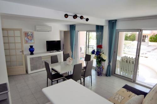 un salon avec une table, des chaises et une télévision dans l'établissement Modern apartment with terrace and beach 5 min away, à Fréjus