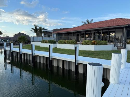 a house with a dock next to a body of water at Waterfront Tip Lot Treasure w/ Southern Sunshine in Henry Key