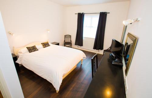 a bedroom with a bed and a television in it at Gray Manor Hotel in Cholderton