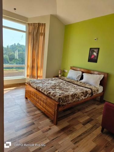 a bedroom with a bed and a large window at Dwarka Home Stay in Ooty