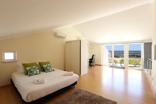 a white bedroom with a bed and a balcony at Bahia's House in Salir de Porto