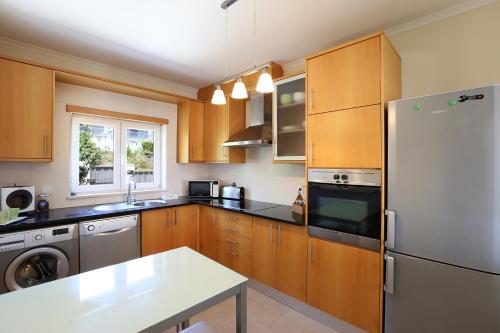 a kitchen with wooden cabinets and a white refrigerator at Bahia's House in Salir de Porto