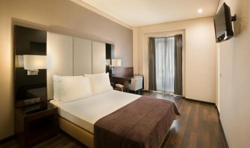 a hotel room with a large bed and a desk at TURIM Restauradores Hotel in Lisbon