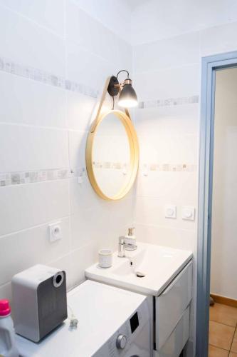 une salle de bain blanche avec un lavabo et un miroir dans l'établissement Les volets blancs, à Lamalou-les-Bains