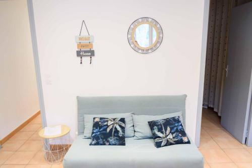 - un canapé avec deux oreillers et un miroir mural dans l'établissement Les volets blancs, à Lamalou-les-Bains
