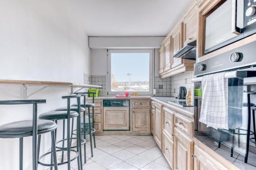 een keuken met houten kasten en barkrukken bij GuestReady - Tranquil Escape in the City in La Mulatière