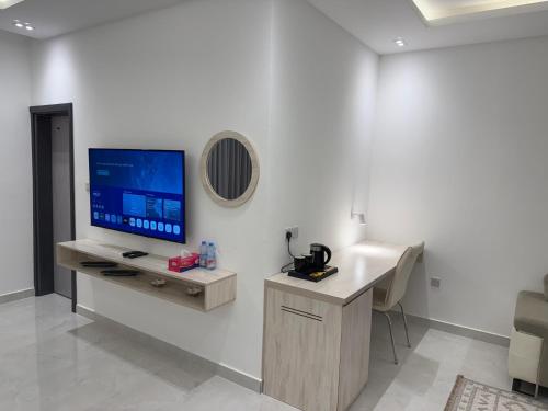 a living room with a tv on a white wall at Oriental Nights Rest House in Al Wāşil