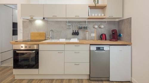 une cuisine avec des armoires blanches et un comptoir en bois dans l'établissement L'Atelier Lumière - Hypercentre - 3 pers, à Troyes