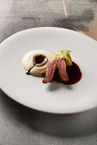a white plate with food on a table at LA CHENEAUDIÈRE - Hôtel Spa - Relais & Châteaux - Restaurant étoilé in Colroy-la-Roche