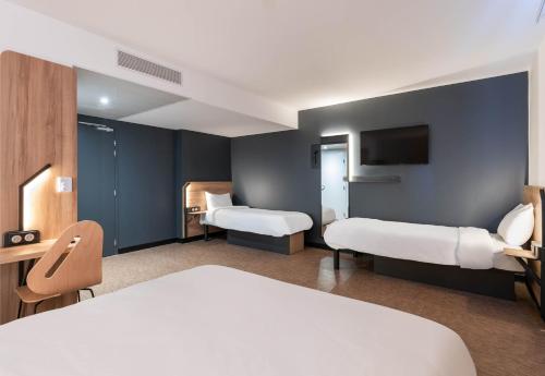 a hotel room with two beds and a tv at B&B HOTEL Massieux Genay in Genay