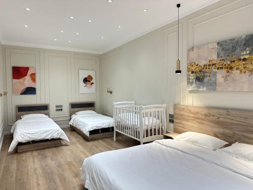 a bedroom with two beds and two cribs at MegaPark Appartments in Almaty