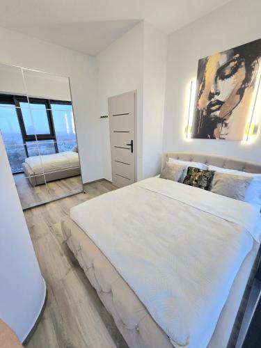 a white bedroom with a large bed and a mirror at Hanza Tower AJP Glamour apartment high floor in Szczecin