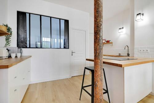 une cuisine avec des armoires blanches et une fenêtre dans l'établissement Loft d'Exception pour 6 Personnes - Voltaire 11e, à Paris