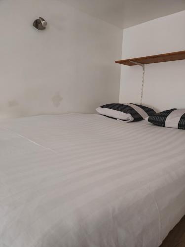 a white bed with black and white pillows on it at Chez Nahiko STUDIO Paris Massy Palaiseau in Palaiseau
