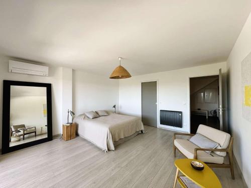une chambre avec un lit, une chaise et un miroir dans l'établissement La Vigie, villa pour 8 personnes avec piscine chauffée et vue mer à La Londe-Les-Maures, à La Londe-les-Maures