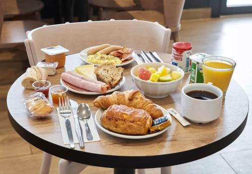 a table topped with plates of breakfast foods and drinks at B&B HOTEL Bois d'Arcy Saint Quentin en Yvelines in Bois-dʼArcy