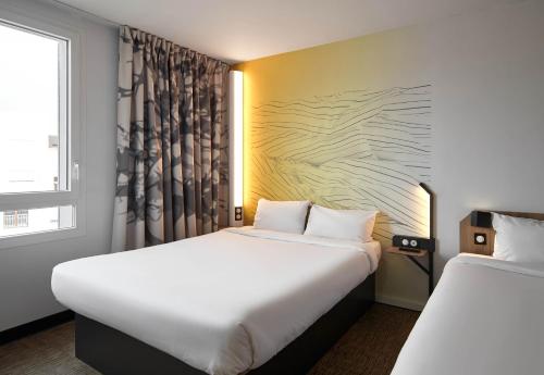 a hotel room with two beds and a window at B&B HOTEL Bois d'Arcy Saint Quentin en Yvelines in Bois-dʼArcy