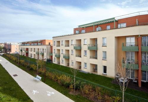 a row of apartment buildings with a sidewalk at B&B HOTEL Bois d'Arcy Saint Quentin en Yvelines in Bois-dʼArcy
