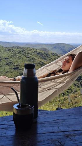 a woman sleeping in a hammock with a bottle of water at Estancia Altos del Durazno in Estancia Grande