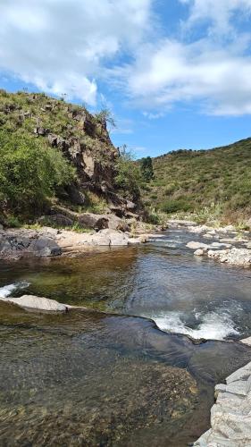 a stream of water with rocks and trees on a hill at Estancia Altos del Durazno in Estancia Grande