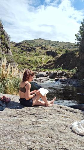 a woman in a bikini sitting on a rock next to a river at Estancia Altos del Durazno in Estancia Grande