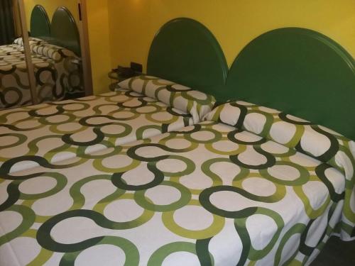 a bed with a green and white comforter and pillows at Hotel VillaPaloma in La Virgen del Camino