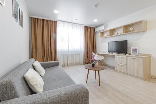 a living room with a couch and a tv at Y'estoria апарт-отель, район EXPO центра in Astana
