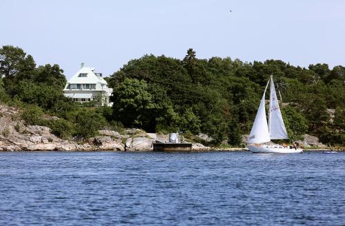 a sail boat on the water with a house in the background at Idöborgs Stuguthyrning in Nämdö