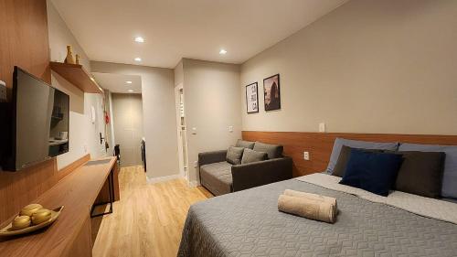 a bedroom with a bed and a tv and a couch at Em frente à praia - conforto, localização e vista in Rio de Janeiro