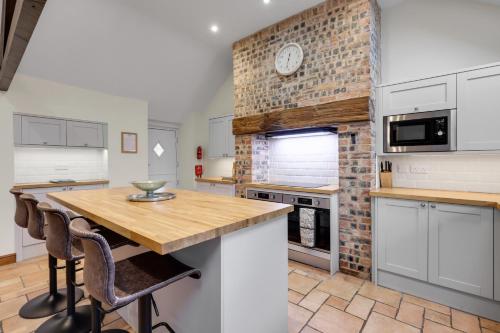 a kitchen with white cabinets and a brick wall at The Orchard - North East Escapes in Morpeth