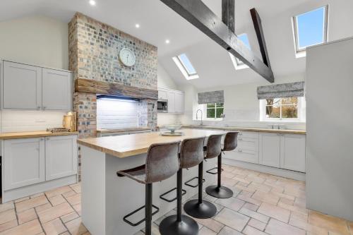 a kitchen with white cabinets and a counter with bar stools at The Orchard - North East Escapes in Morpeth
